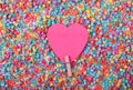 Beautiful greeting card design of Sweet Pink Heart pinned with a clothes peg in a sea of multicoloured beads. Copy Space for Texts