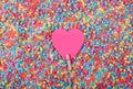 Beautiful greeting card design of Sweet Pink Heart pinned with a clothes peg in a sea of multicoloured beads. Copy Space for Texts