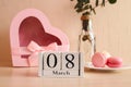 Beautiful greeting card for Women's Day. Wooden calendar 08 March, a glass of champagne, french macaroon pastry and a