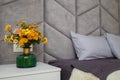 Beautiful grey bedroom, bed, pillows, soft fabric headboard, autumn bouquet of yellow chrysanthemums in green vase near. Modern Royalty Free Stock Photo