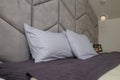 Beautiful grey bedroom, bed, pillows, soft fabric headboard. Modern interior design, close up shot Royalty Free Stock Photo