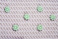 Beautiful grey knitted texture. Elegant pattern with elaborately bound and sewn green flowers. Crochet close-up. background for