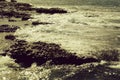 Beautiful grey sea stormy waves splash against black stony shore Royalty Free Stock Photo