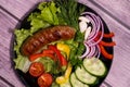 Beautiful grilled sausages on a black plate with vegetables and a background of boards