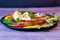 Beautiful grilled sausages on a black plate with vegetables and a background of boards