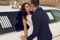 Beautiful groom and bride in wedding clothes posing beside a car Royalty Free Stock Photo