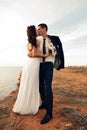Beautiful groom and bride in wedding clothes posing on sea coast Royalty Free Stock Photo