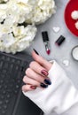 Beautiful groomed woman`s hands with dark glitter polish nail design