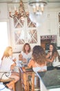 Beautiful group of women sitting at kitchen drinking cup of coffee speaking and smiling Royalty Free Stock Photo