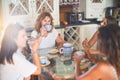 Beautiful group of women sitting at kitchen drinking cup of coffee speaking and smiling Royalty Free Stock Photo