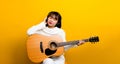 guitarist Asian ethnic woman Singing and playing guitar while sitting in a chair cross-legged. background color Music Royalty Free Stock Photo