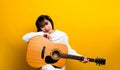 guitarist Asian ethnic woman Singing and playing guitar while sitting in a chair cross-legged. background color Music Royalty Free Stock Photo