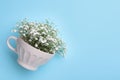 Beautiful gypsophila in white cup on light blue background, top view. Space for text Royalty Free Stock Photo