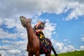 Beautiful gypsy girl on a horse in field with green glass in summer day and blue sky and white clouds background. Model in ethnic Royalty Free Stock Photo