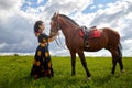 Beautiful gypsy girl with a horse in field with green glass in summer day and blue sky and white clouds background. Model in Royalty Free Stock Photo