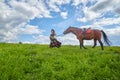 Beautiful gypsy girl walking with a horse in field with green glass in summer day and blue sky and white clouds background. Model Royalty Free Stock Photo