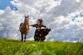 Beautiful gypsy girl walking with a horse in field with green glass in summer day and blue sky and white clouds background. Model Royalty Free Stock Photo
