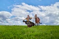 Beautiful gypsy girl walking with a horse in field with green glass in summer day and blue sky and white clouds background. Model Royalty Free Stock Photo