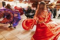 Beautiful gypsy girls dancing in traditional red floral dress at wedding reception in restaurant. Woman performing romany dance