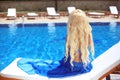 Beautiful Hair. Beauty blond woman with luxurious long hair sitting on beach bed, looking at swimming pool. Royalty Free Stock Photo