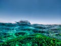 Beautiful half-underwater scene with a floating boat against the background of the blue sky.