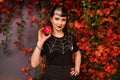 Beautiful halloween girl in black pin up clothes with dead red apple in the hand on autumn leaves background alone Royalty Free Stock Photo