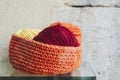 Hand knitted wool basket in orange with balls of wool Royalty Free Stock Photo