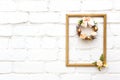 Beautiful hand made everlasting dry wreath made of dyed eggs and flowersin golg frame on the white wall background with copy space