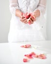 Beautiful hand with perfect french manicure on treated nails holding rose flower petals. isolated on white background Royalty Free Stock Photo