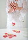 Beautiful hand with perfect french manicure on treated nails holding rose flower petals. isolated on white background Royalty Free Stock Photo