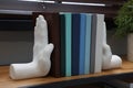 Beautiful hand shaped bookends with books on shelf indoors