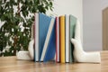 Beautiful hand shaped bookends with books on wooden table indoors