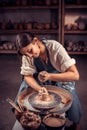 Beautiful handicraftsman master making pottery, sculptor from wet clay on wheel. National craft.