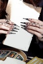 Beautiful hands with long acrylic witch black nails holding a white sheet in the hands of