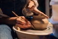 Beautiful hands of a young girl potter in the process of sculpting a vase with clay and tools.