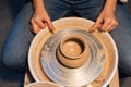 Beautiful hands of a young girl potter in the process of sculpting a vase with clay and tools.