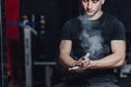 Beautiful handsome young athlete dressed in black t-shirt. During this time, sitting on the tires and applying talcum to Royalty Free Stock Photo