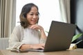 Beautiful and happy Asian-aged woman using laptop in her living room, browsing internet Royalty Free Stock Photo