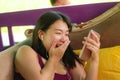 Beautiful happy Asian Korean student girl using internet social media app networking with hand phone outdoors at cool cafe smiling Royalty Free Stock Photo