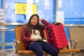 Beautiful and happy Asian Korean tourist woman with travel suitcase in airport sitting at departures waiting for flight smiling ch Royalty Free Stock Photo