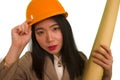 Beautiful and happy Asian Korean woman in hardhat holding building blueprints as architect engineer or constructor supervisor in Royalty Free Stock Photo