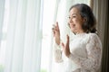 Beautiful and happy Asian middle-aged woman looking out the window in the morning Royalty Free Stock Photo