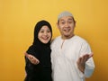 Happy Asian muslim couple wearing casual clothes smiling friendly offering handshake as greeting and welcoming