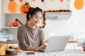 A woman is working on her computer at a kitchen table during the Halloween season at home