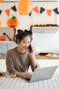 A beautiful and happy Asian woman is working from home on Halloween weekend Royalty Free Stock Photo