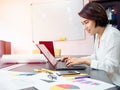 Beautiful happy Asian woman working with laptop computer on table in meeting room