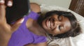 Beautiful and happy black Afro American woman lying relaxed on bed using internet mobile phone smiling cheerful networking social Royalty Free Stock Photo