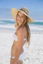 Beautiful happy blonde on the beach in white bikini and sunhat
