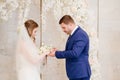 beautiful and happy bride and groom exchange rings in an arch of flowers Royalty Free Stock Photo