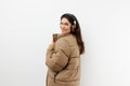 beautiful happy brunette listens to music in brown headphones while standing in a warm winter stylish jacket with her